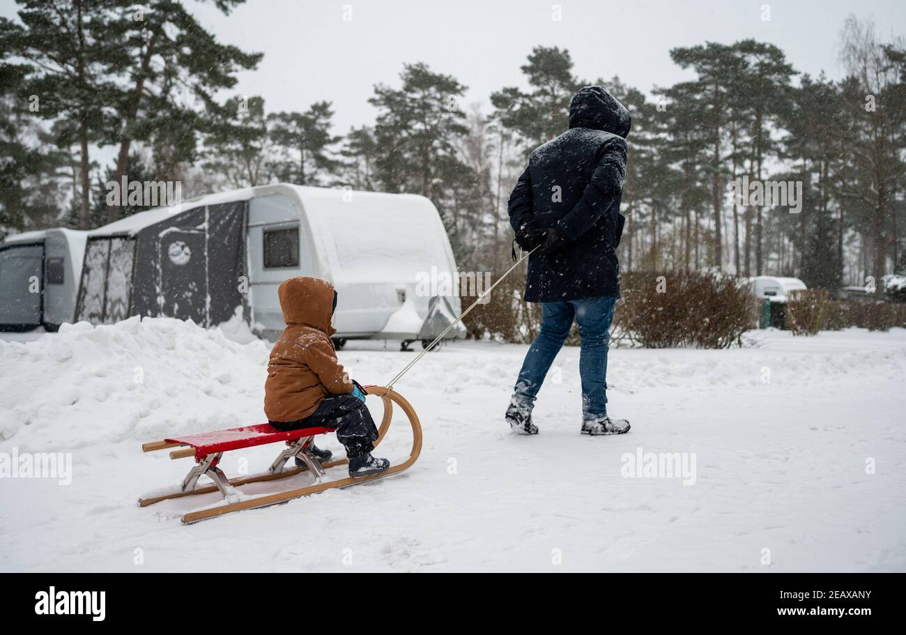 Wietzendorf, Germania. 8 febbraio 2021. Un uomo tira suo figlio sulla slitta sui terreni del South Sea Camp. In inverno ci è poca attività ai campeggi, soltanto alcuni bookers tutto l'anno sono da trovare. Il turismo è proibito in Corona Times. Credit: Philippe Schulze/dpa/Alamy Live News Foto Stock