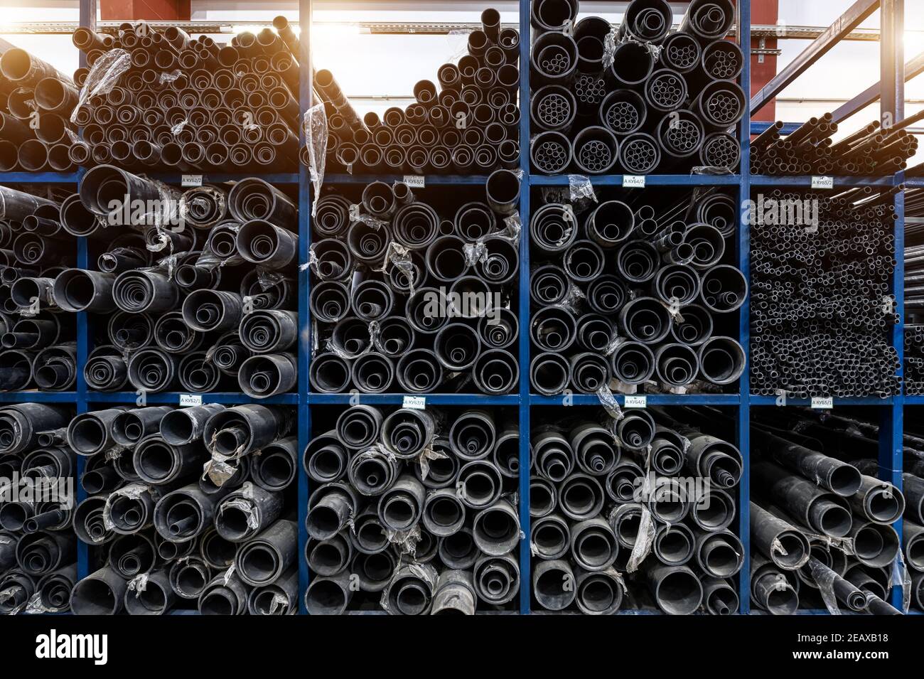Scaffale da magazzino con tubi in plastica. I tubi sono neri Foto Stock