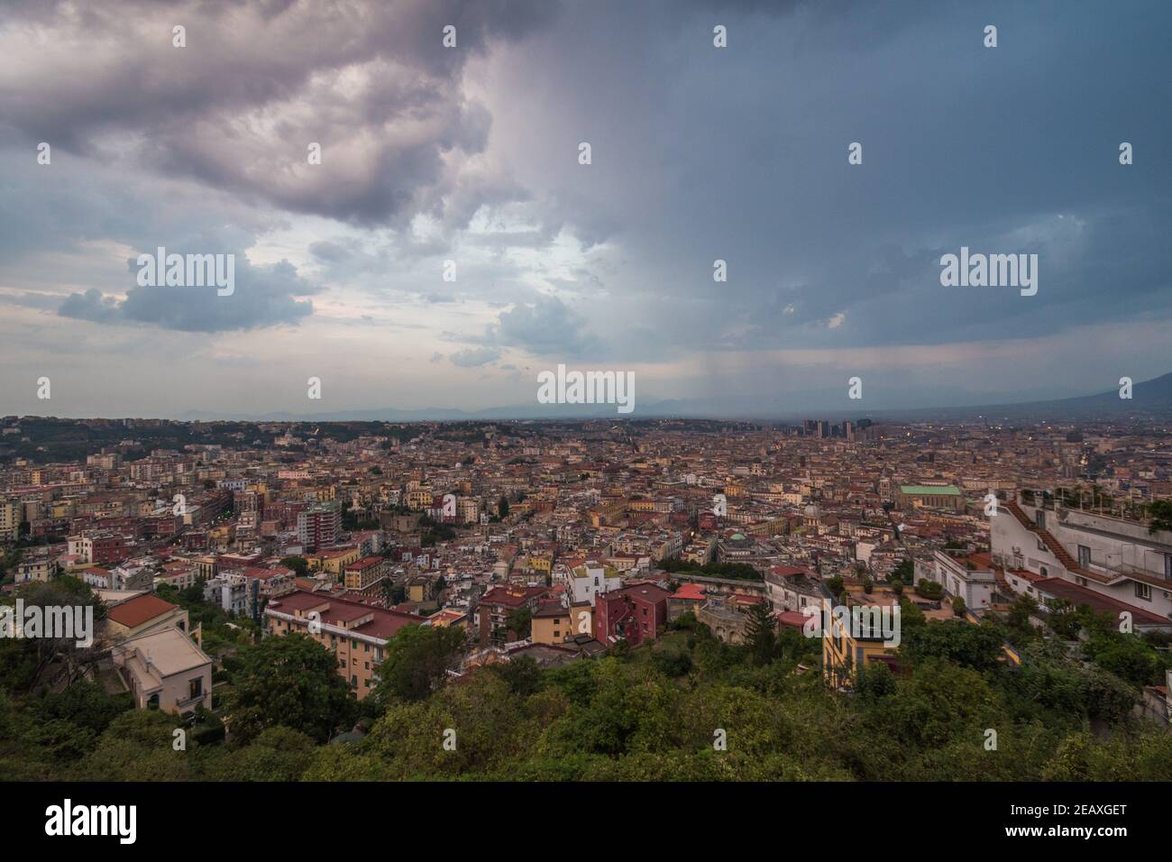 Vista panoramica sugli edifici e sul verde della città di Napoli, Italia meridionale, durante un tramonto nuvoloso. Foto Stock