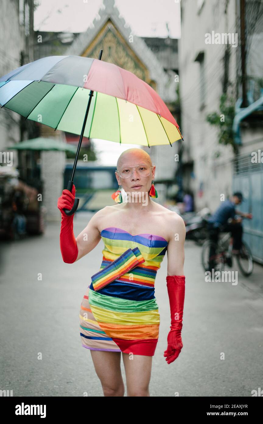 Ritratto di una regina asiatica vestita con abiti di colore arcobaleno, indossando guanti rossi e tenendo un ombrello di colore arcobaleno a Bangkok Thailandia. Foto Stock