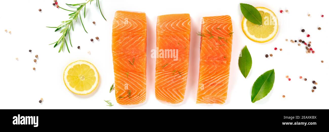 Panorama del salmone crudo con erbe, limoni e spezie, top shot su sfondo bianco Foto Stock