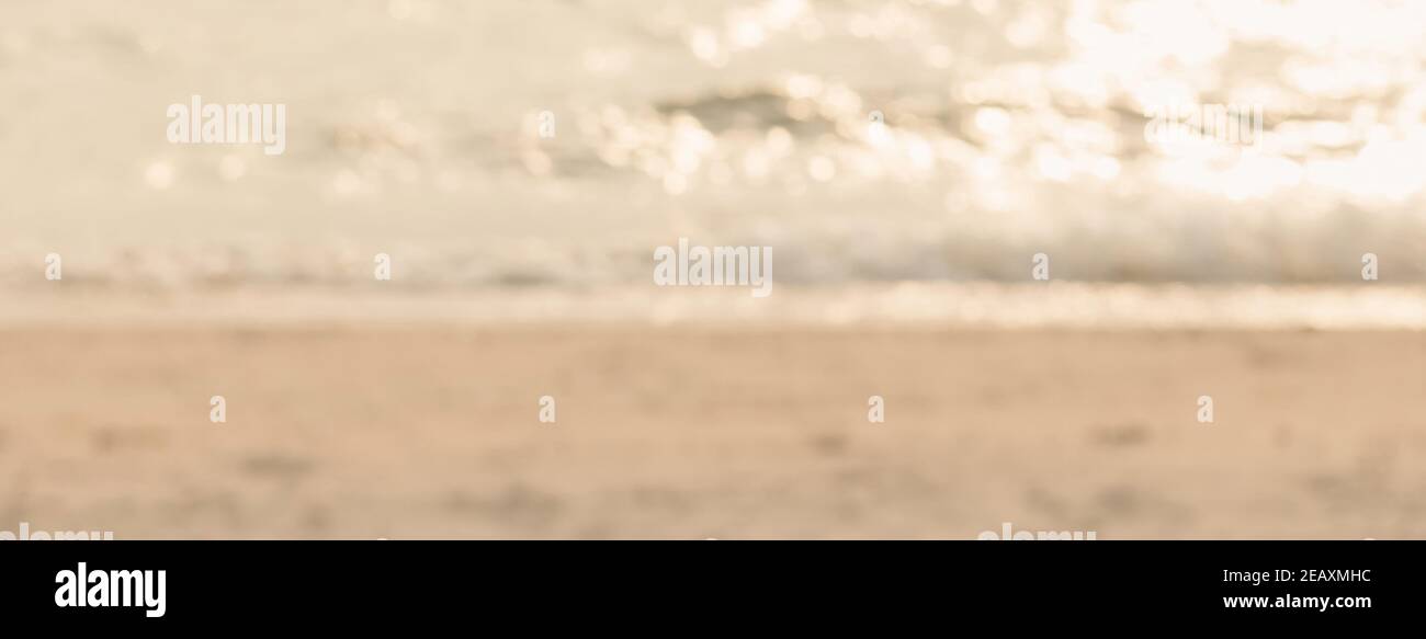 Offuscate la sabbia marrone chiaro e l'acqua di mare scintillante sulla spiaggia in estate banner backround Foto Stock