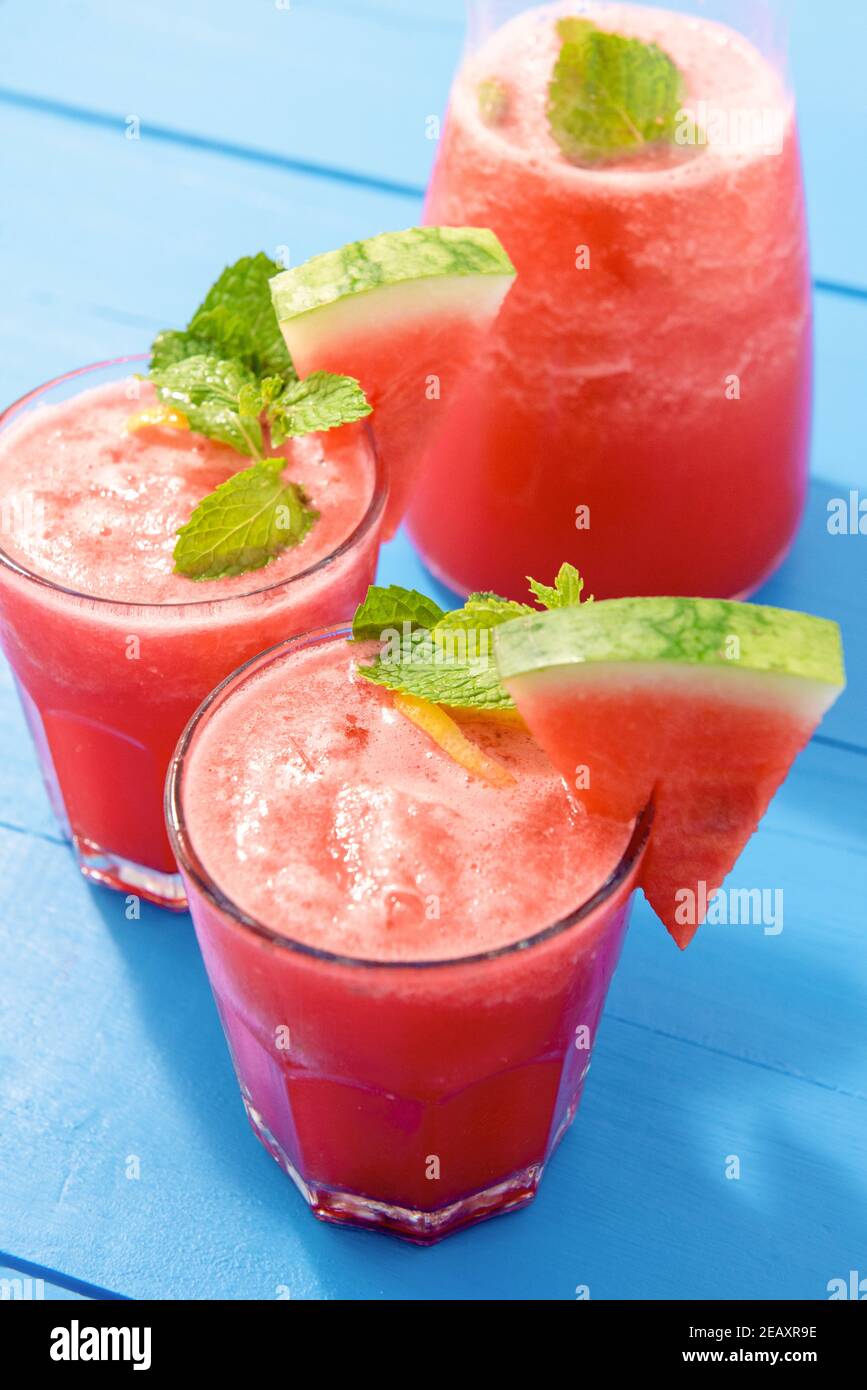 Rinfrescanti e fredde bevande all'anguria tropicale estive servite sul blu tavolo di legno Foto Stock