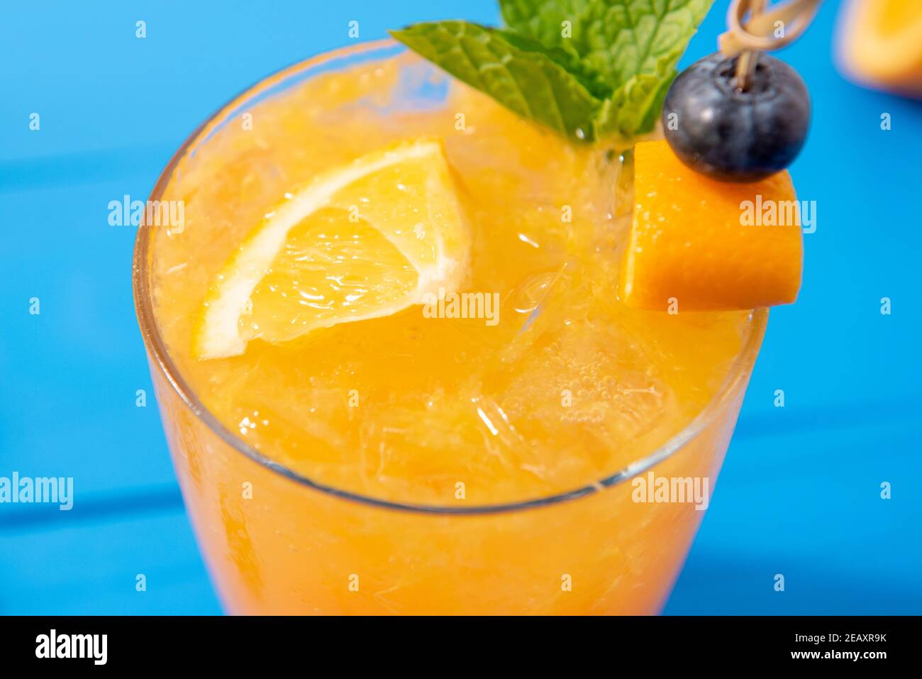 Primo piano di ghiacciato arancio rinfrescante drink essere servito su tavolo di legno blu Foto Stock