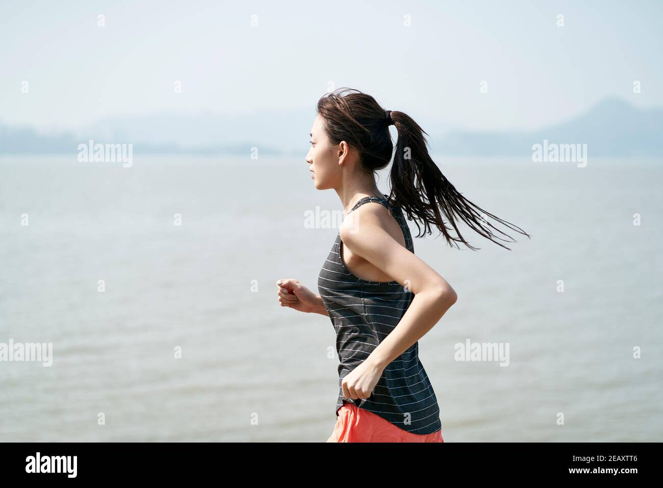 giovane donna asiatica corridore femminile in riva al mare Foto Stock