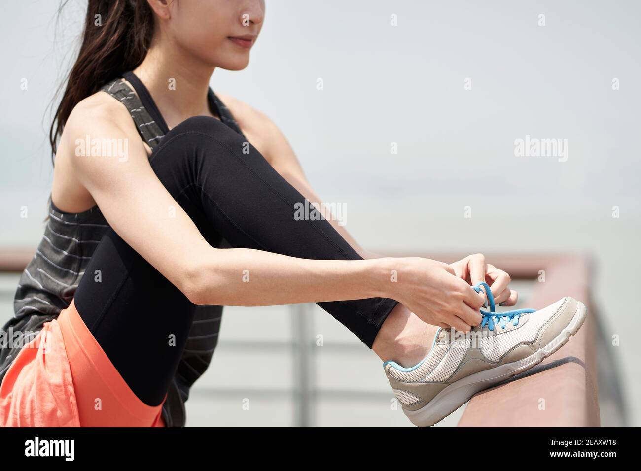 giovane donna asiatica in abbigliamento sportivo allacciandosi prima di esercitarsi Foto Stock