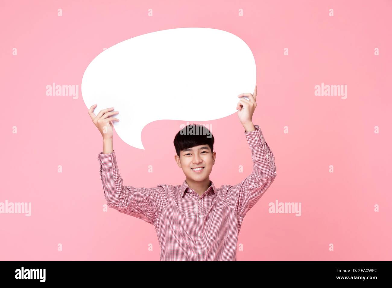 Felice sorridente giovane bell'uomo asiatico tenendo bolla di parola con spazio vuoto per il testo su sfondo rosa Foto Stock