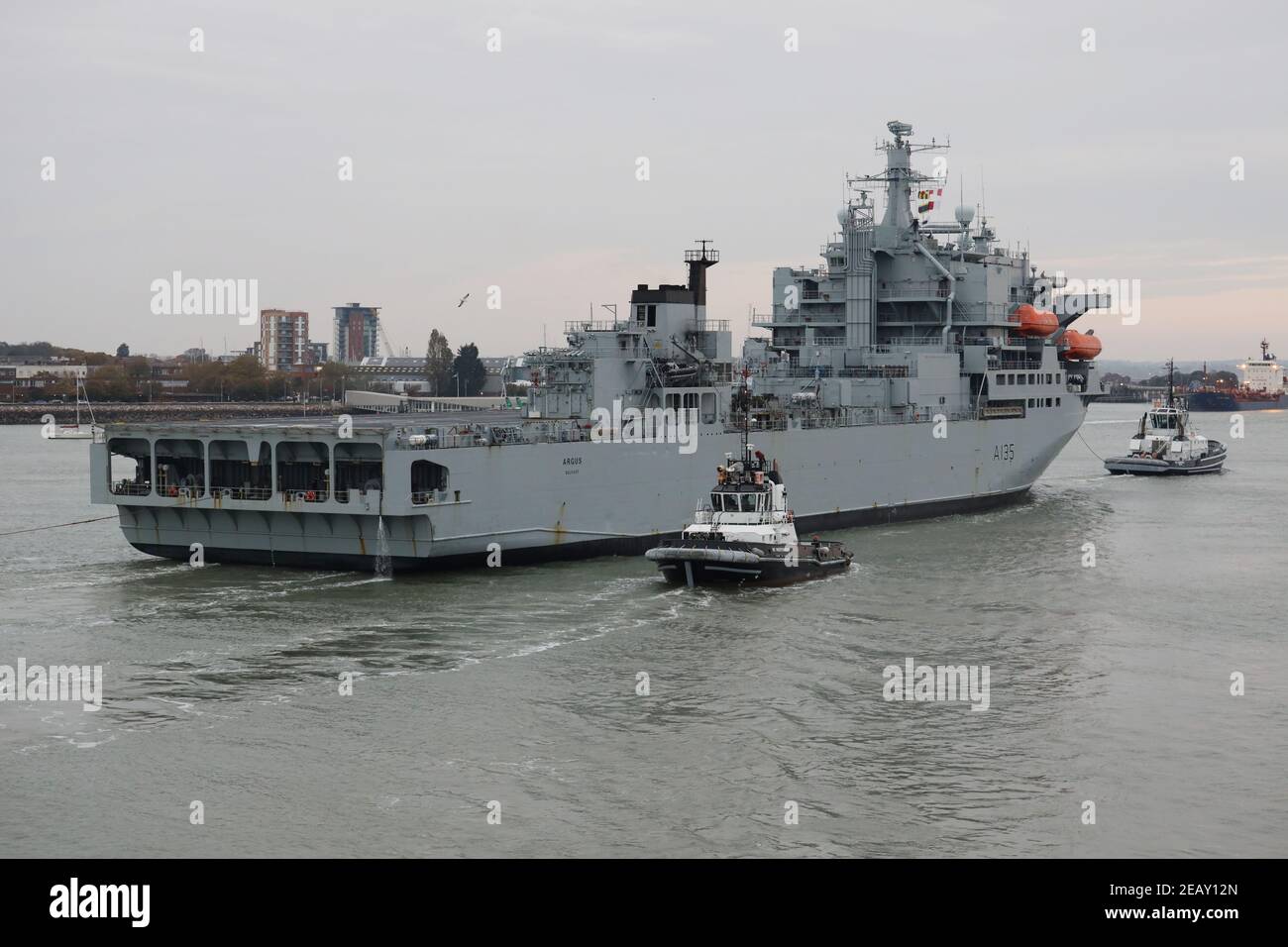 I Tugs guidano la nave ausiliaria della flotta reale ARGUS verso il Il molo reale della Principessa della base navale Foto Stock