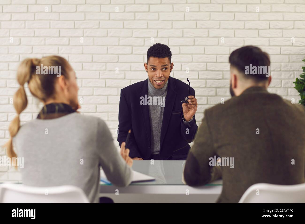 L'uomo giovane e fiducioso con pelle scura comunica e risponde alle domande dei datori di lavoro durante l'intervista. Foto Stock