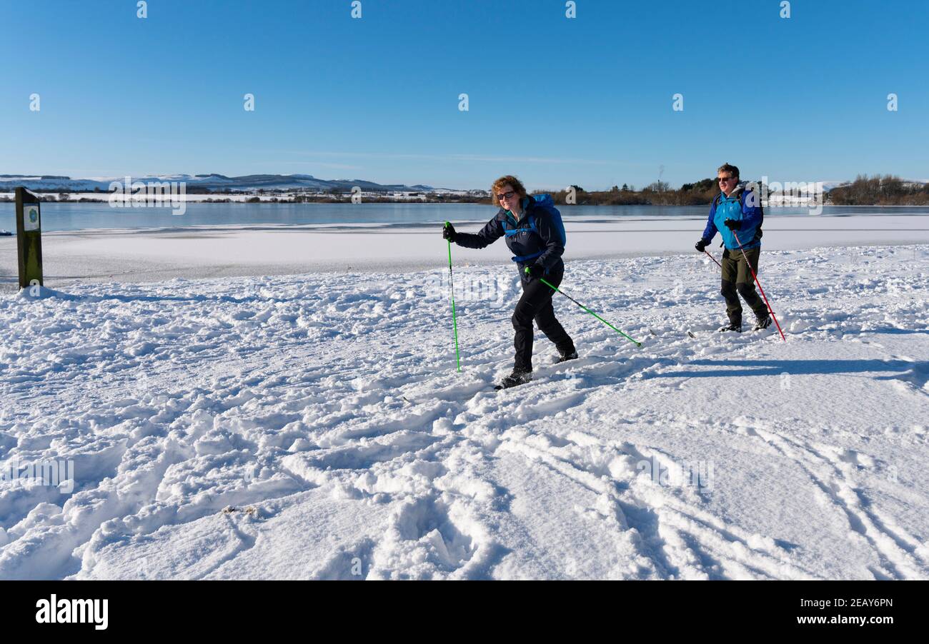 Kinross, Scozia, Regno Unito. 11 Feb 2021. Andrew e Rosie Wood di Perth fanno il massimo delle condizioni fredde perfette per praticare sci di fondo lungo le rive del lago di Loch Leven in una giornata fredda e soleggiata con una temperatura di -7C. Iain Masterton/Alamy Notizie dal vivo Foto Stock