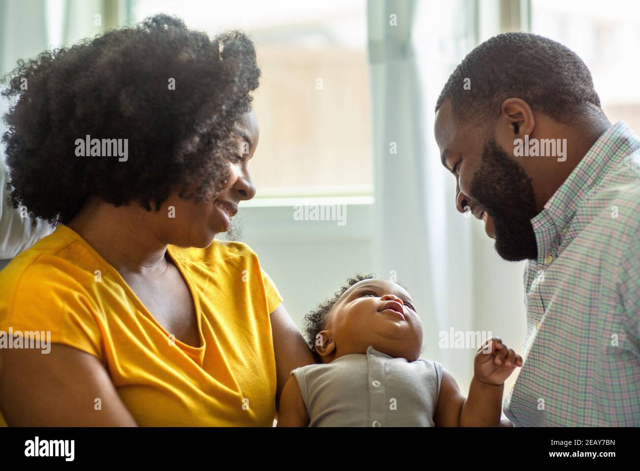 Madre afroamericana e padre che baciano e abbracciano il figlio. Foto Stock