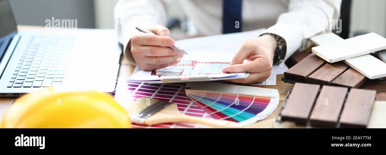 Designer in ufficio siede a tavola con progetto e una tavolozza di colori per gli interni Foto Stock