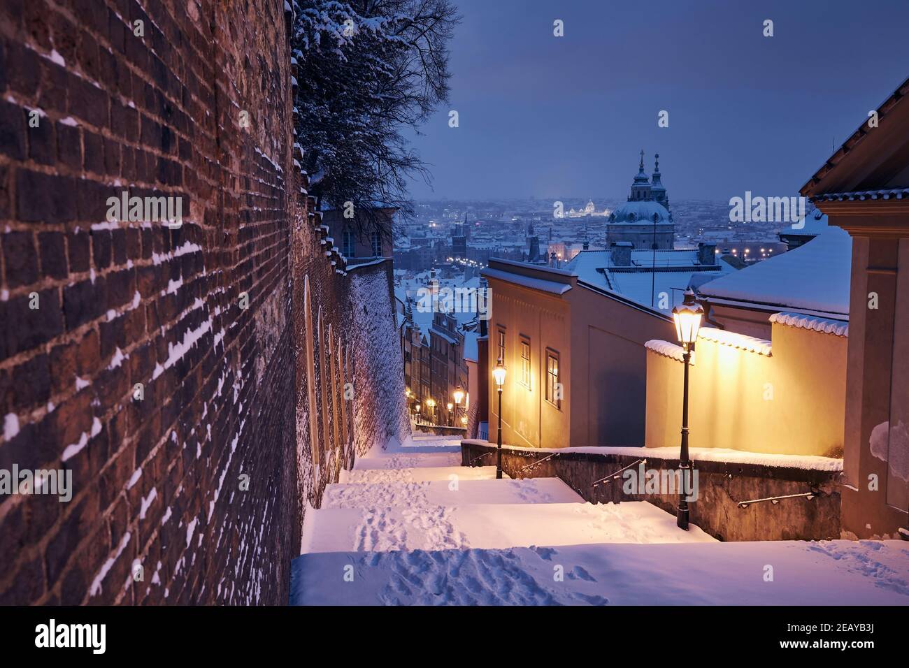 Paesaggio urbano di Praga in inverno. Scalinata storica illuminata contro la città bassa e la città vecchia al mattino presto. Foto Stock