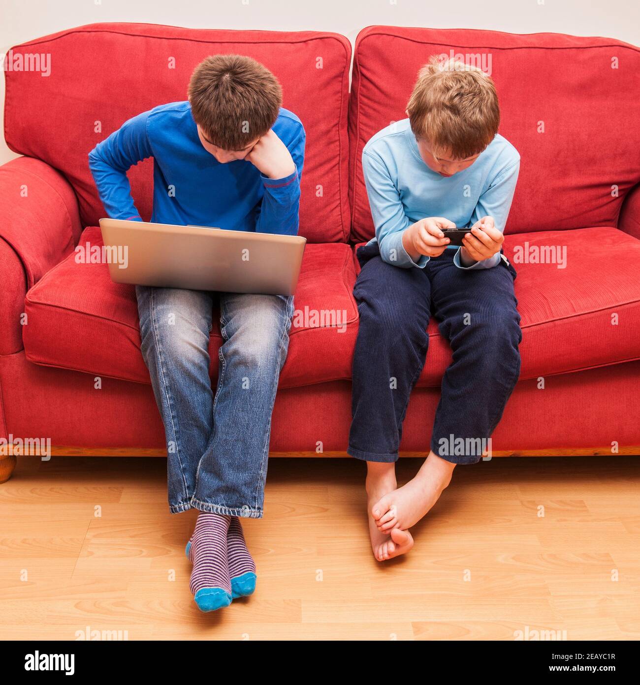 Un ragazzo di 13 anni e i suoi 9 anni fratello che utilizza un computer portatile e un ipod touch Foto Stock