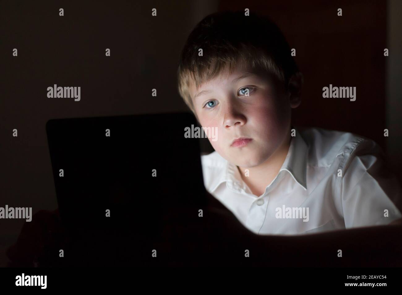 Un ragazzo di 9 anni che usa un tablet nel sera Foto Stock
