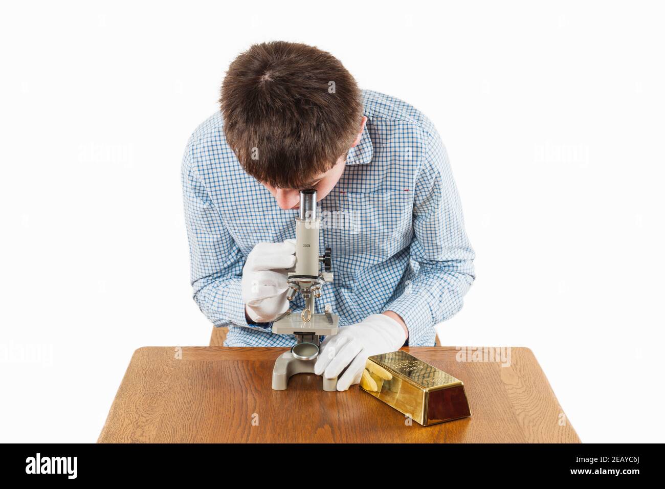 Un ragazzo adolescente che controlla la qualità di un anello d'oro utilizzando un microscopio Foto Stock