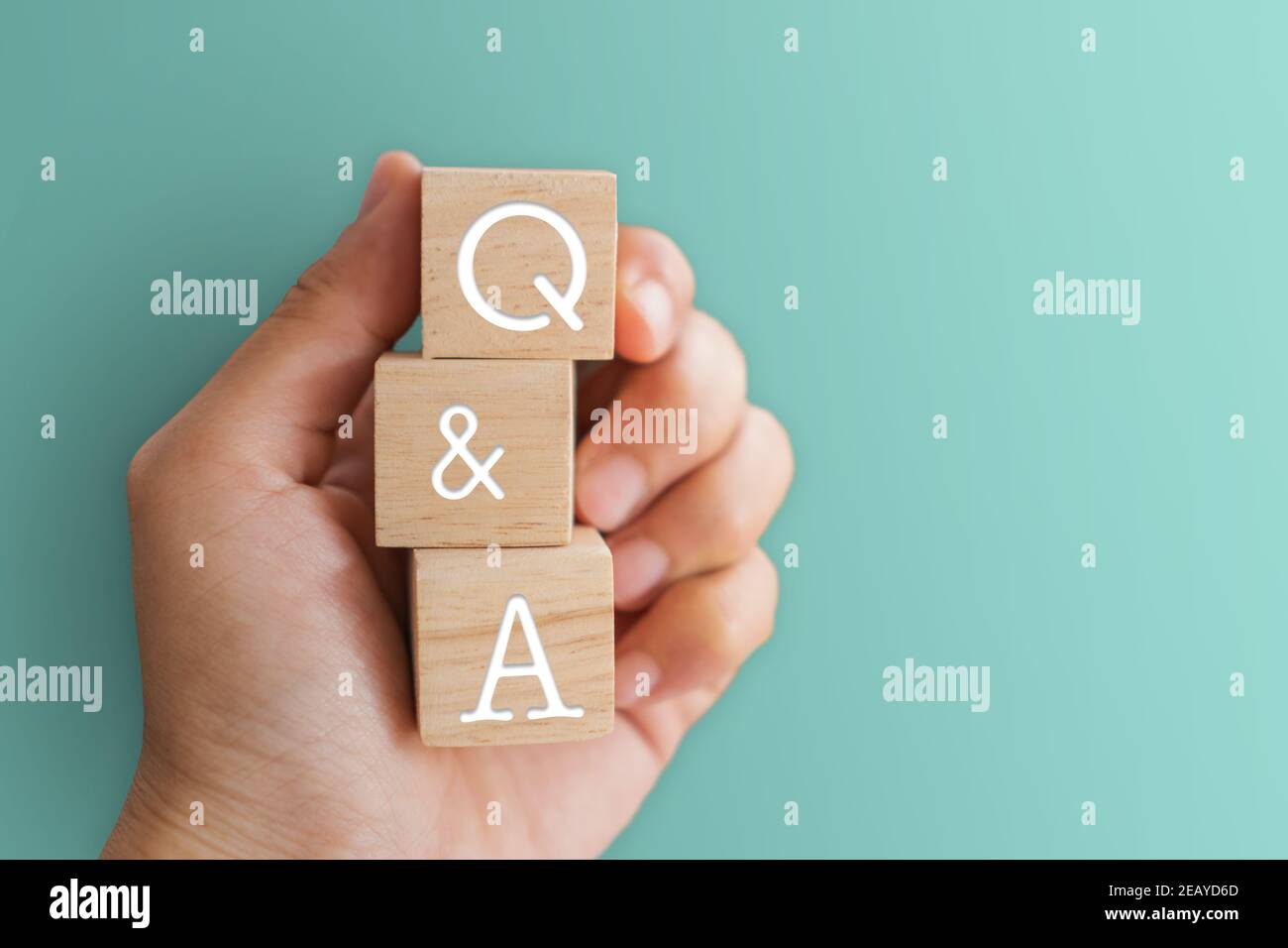 Q e un alfabeto su cubo di legno in mano con sfondo. Concetto di significato di domanda e risposta. Foto Stock