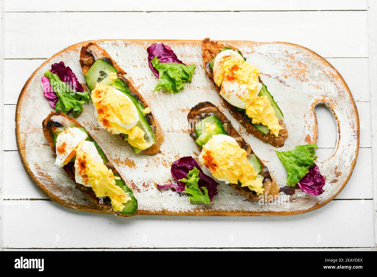 Bruschetta con uova in camicia, cetriolo e funghi fritti con salsa hollandaise. Tasty uova benedetto Foto Stock