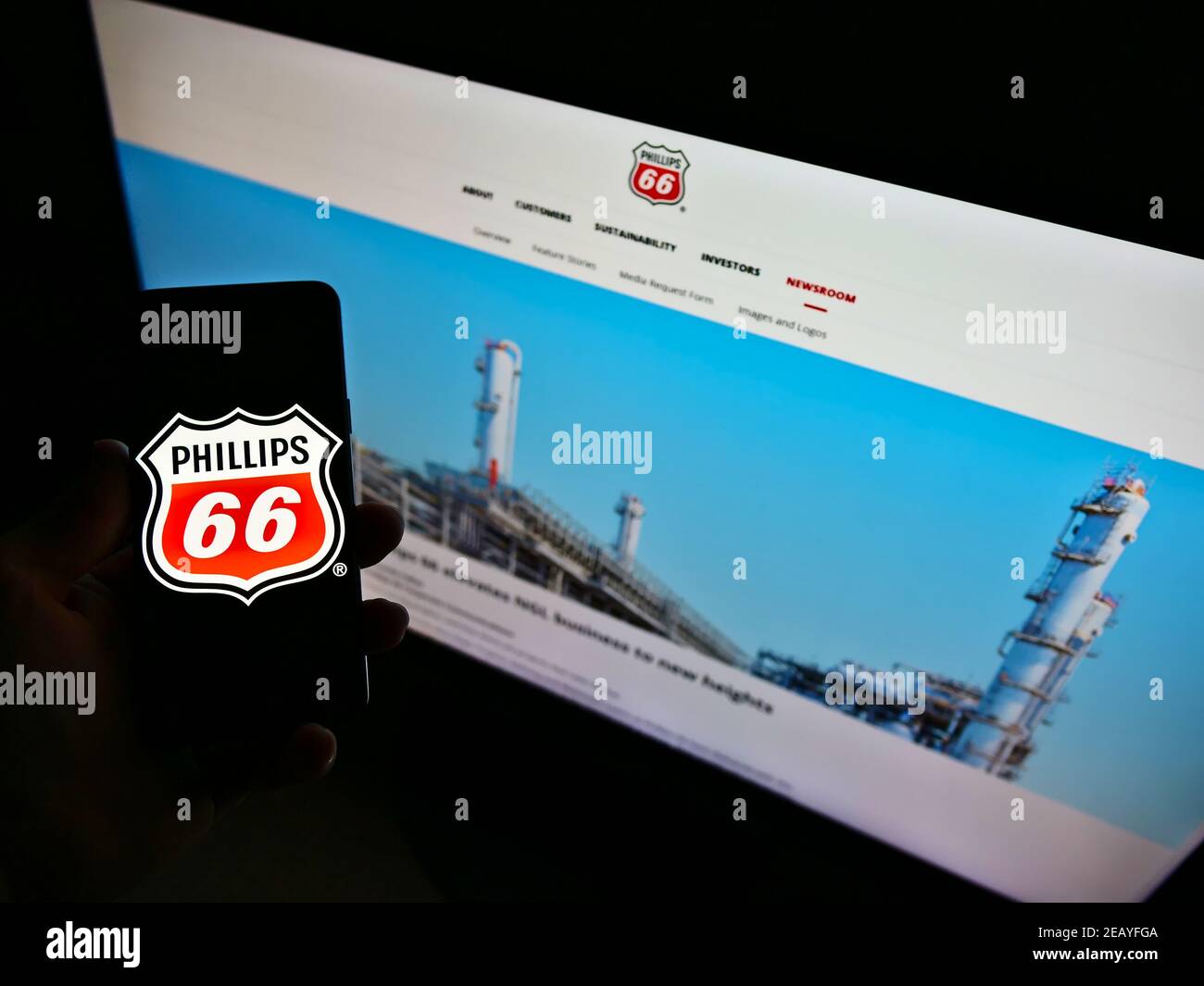 Persona che detiene smartphone con il logo della società americana di petrolio e gas Phillips 66 sullo schermo di fronte al sito web. Mettere a fuoco il display del telefono. Foto Stock
