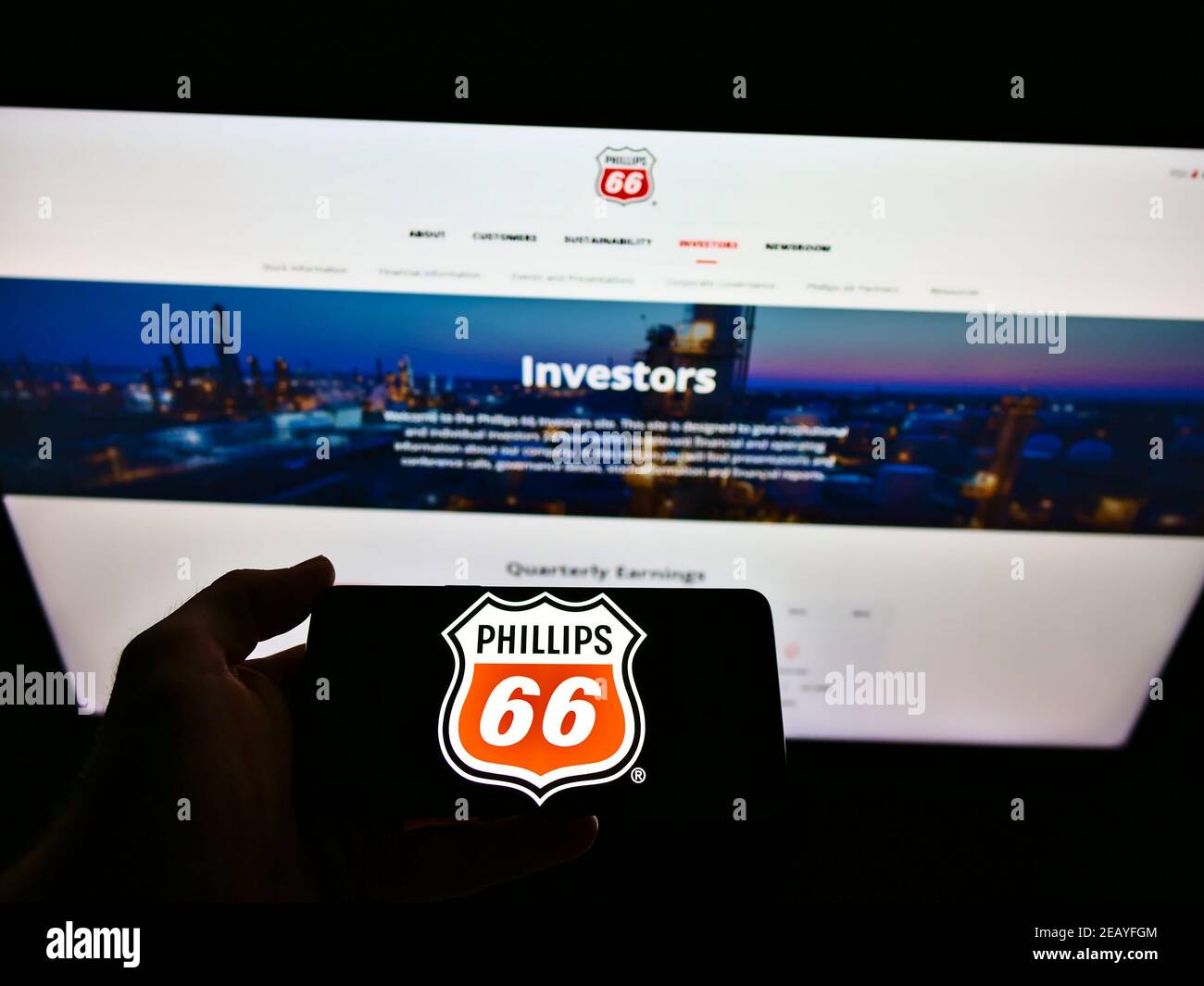Persona che tiene il cellulare con il logo del commercio americano del petrolio e del gas Phillips 66 Company sullo schermo davanti al Web page. Focus sul display del telefono cellulare. Foto Stock