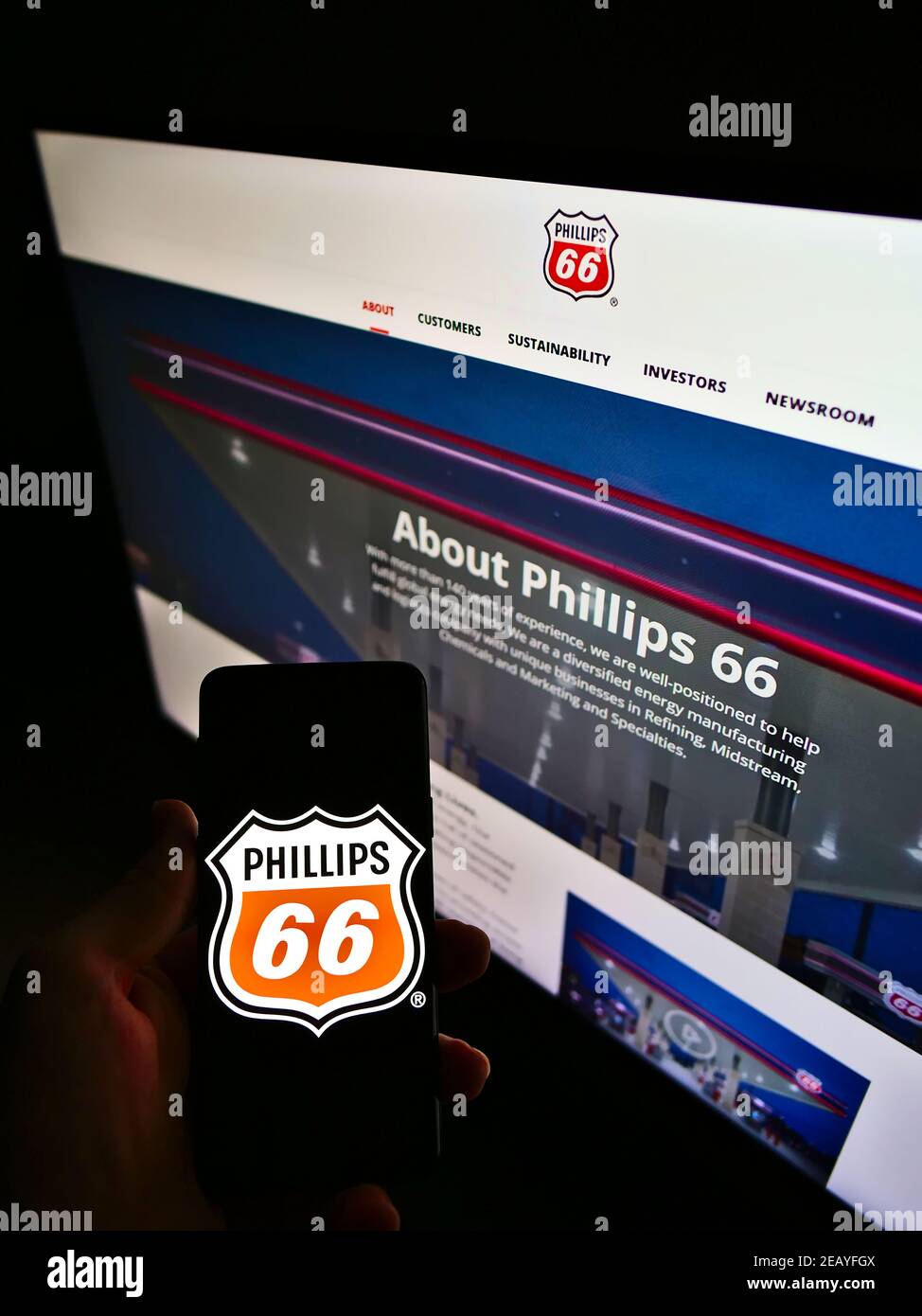 Persona che tiene il telefono mobile con il logo del commercio americano del petrolio e del gas Phillips 66 Company sullo schermo davanti alla pagina web. Mettere a fuoco il display del telefono. Foto Stock