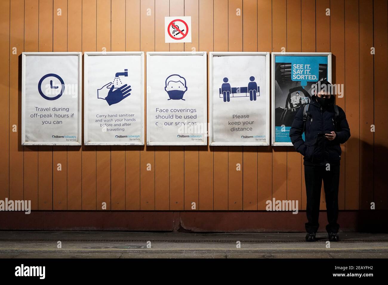 Un uomo si trova accanto ai cartelli informativi del coronavirus sulla piattaforma alla stazione di Moor Street a Birmingham. Data immagine: Mercoledì 10 febbraio 2021. Foto Stock