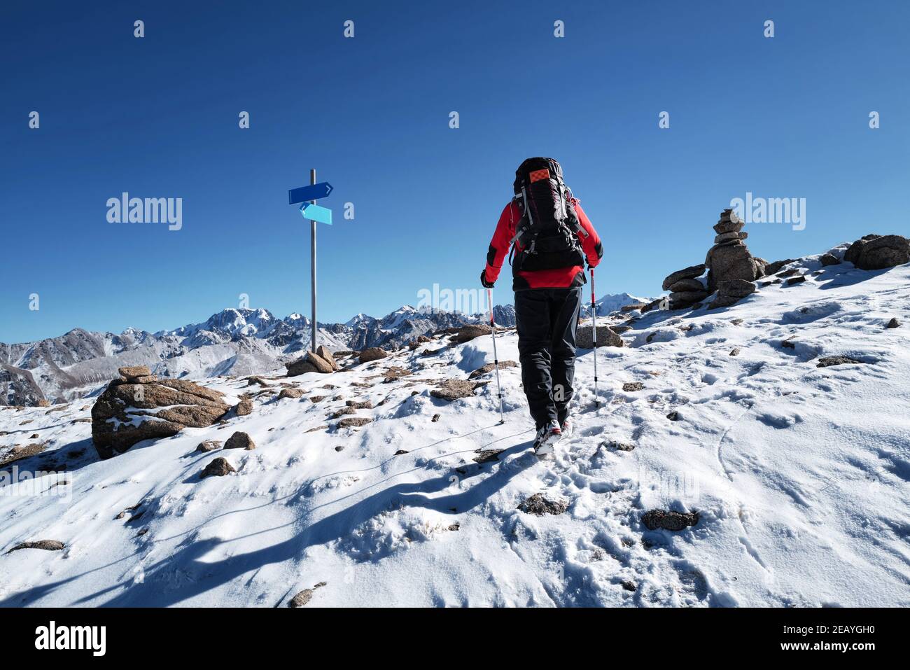 Uomo con zaino che cammina sulla roccia nella bella montagne contro il cielo blu Foto Stock