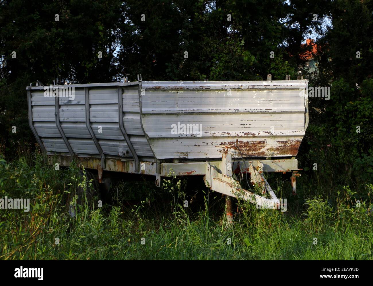 Rimorchio per trattori agricoli arrugginiti in disuso verniciato bianco in un eccesso campo in sole e ombra Foto Stock