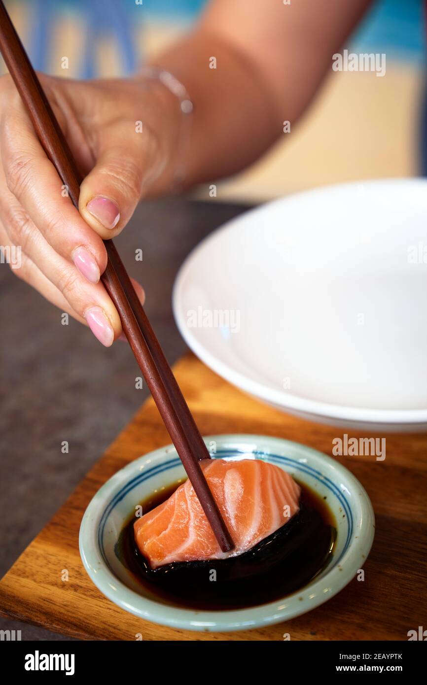 I sashimi di salmone con salsa di soia sono stati raccolti con i chopsticks Foto Stock