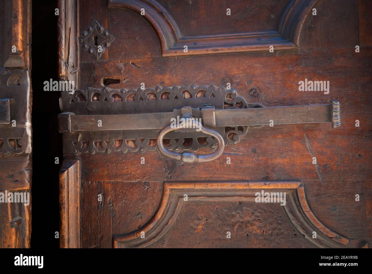 Antica porta in legno con elaborata chiocciola in ferro nella città medievale di Bormio, nelle Alpi, Italia Foto Stock