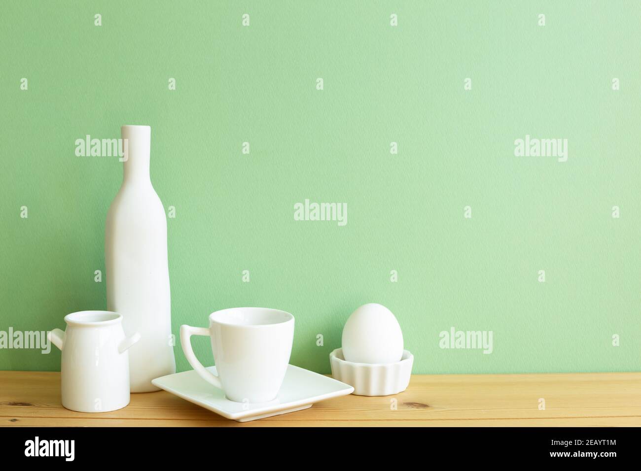 Stoviglie in ceramica bianca su tavolo di legno. Sfondo verde Foto Stock