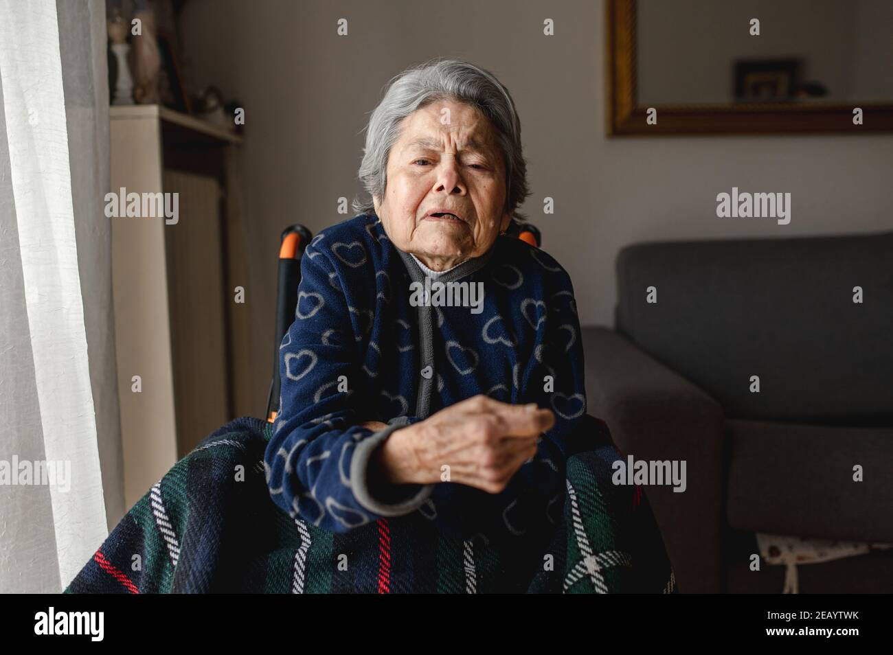 Ritratto vecchia donna malata seduta in sedia a rotelle a casa con viso disorientato e confuso. Terza età, concetto di assistenza per anziani domestici. Foto Stock