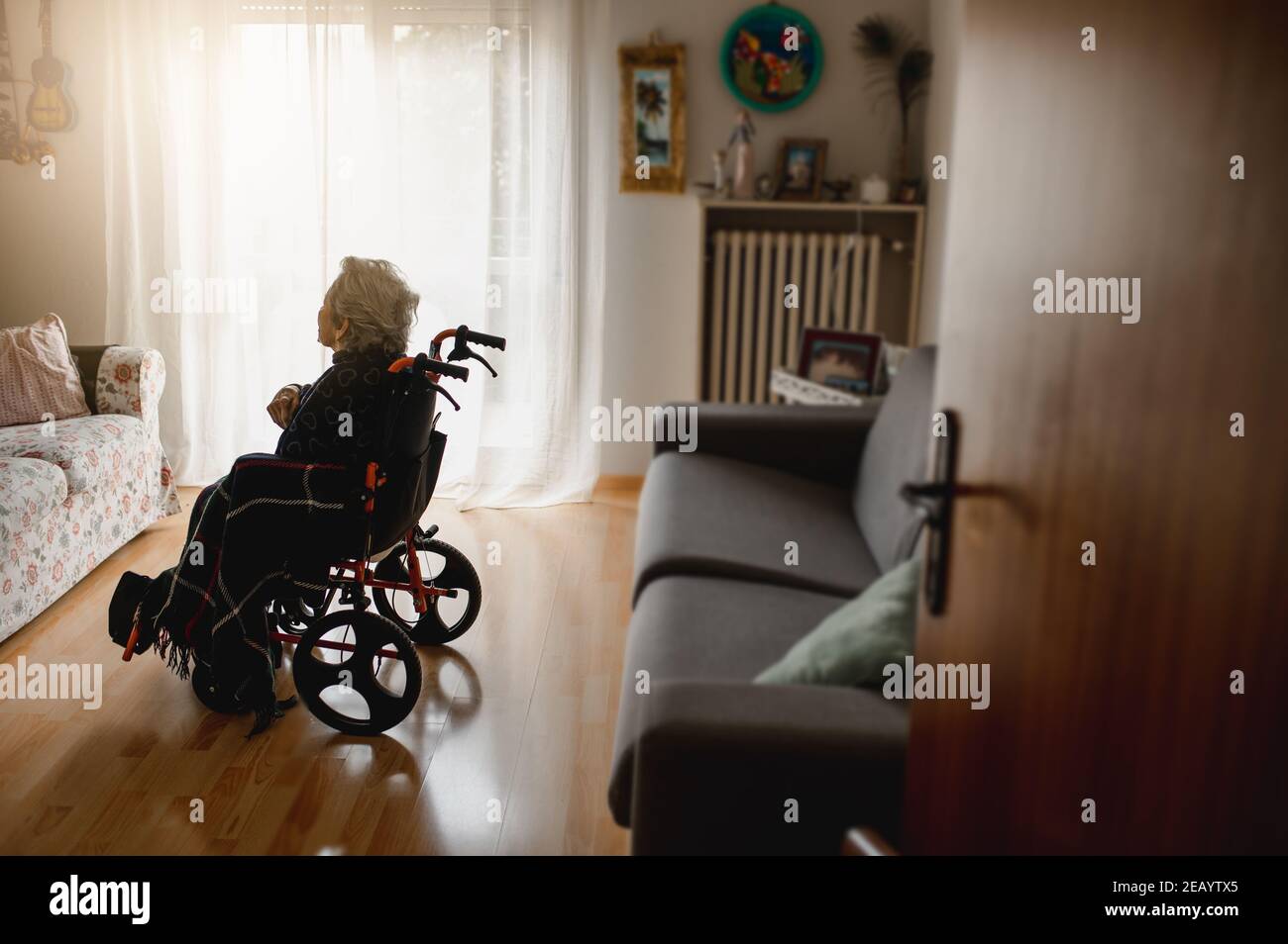 Punto di vista donna anziana malata in sedia a rotelle nella solo nel mezzo della camera domestica Foto Stock
