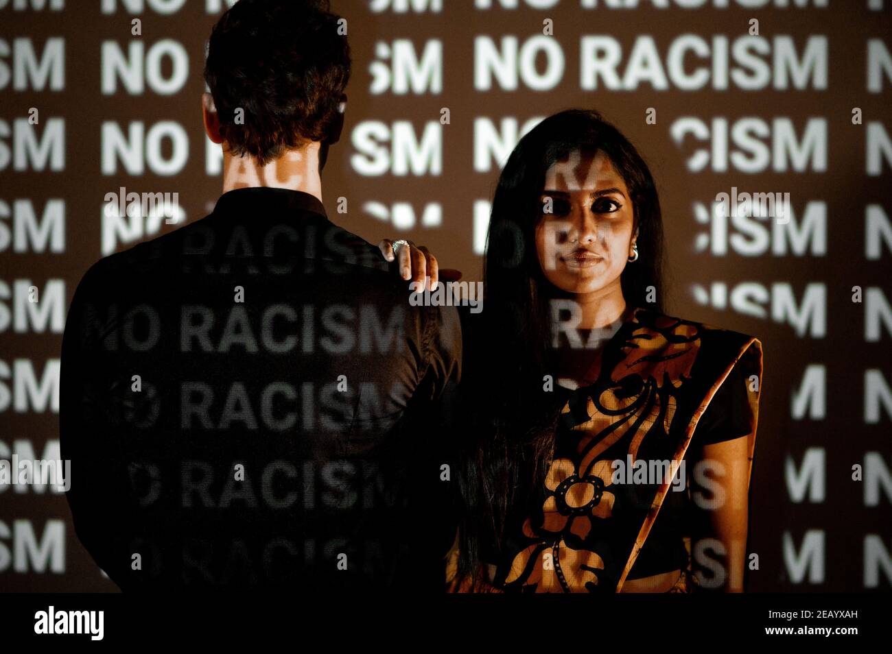 Giovane donna indiana in abito tradizionale guardando la macchina fotografica con il viso serio accanto al bianco uomo. Concetto di discriminazione e violenza contro le donne. Foto Stock