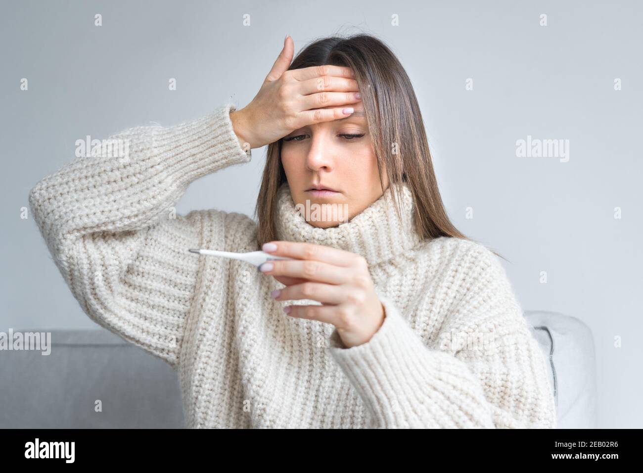 Donna malata malsana con febbre che misura la temperatura con un medico termometro Foto Stock