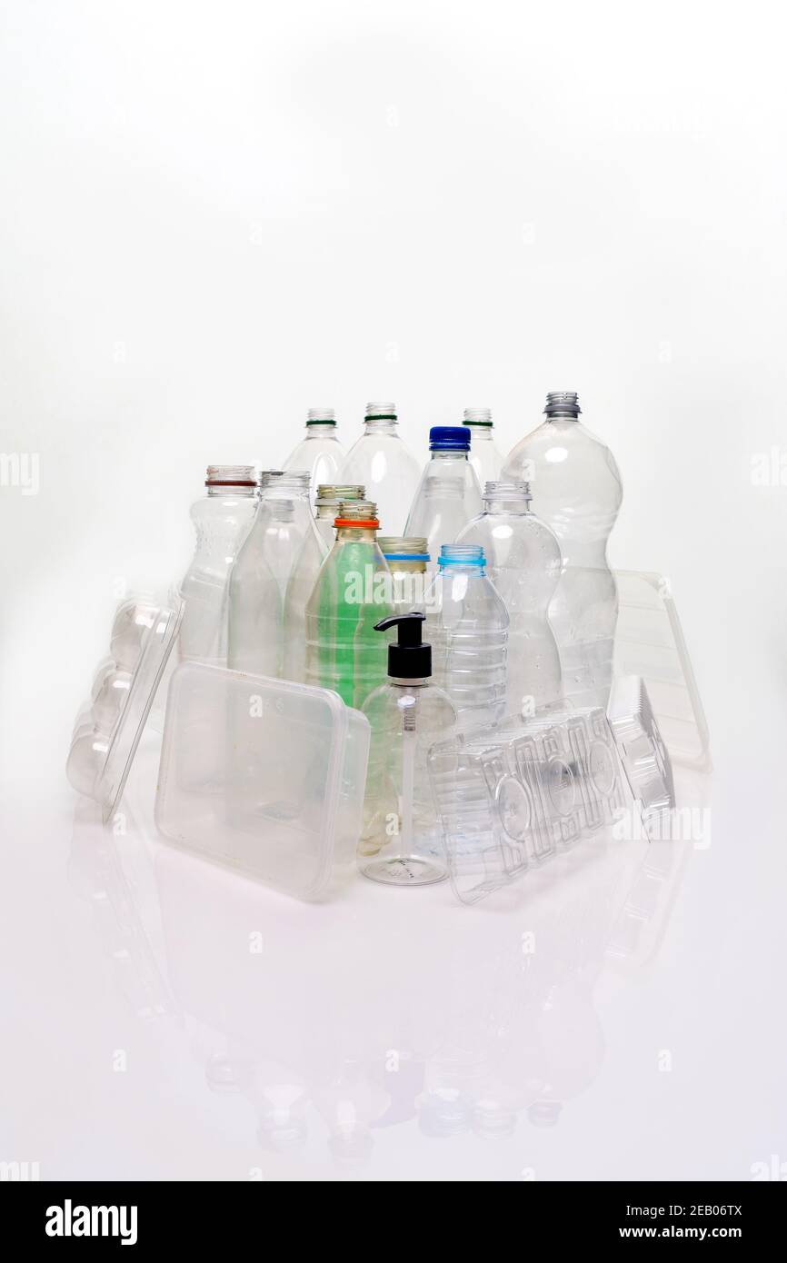 Una collezione di materiale a base di plastica per uso domestico sparato su uno sfondo bianco con riflessi. Flaconi, vassoi per alimenti, contenitori per pompe pronti per il riciclaggio. Foto Stock