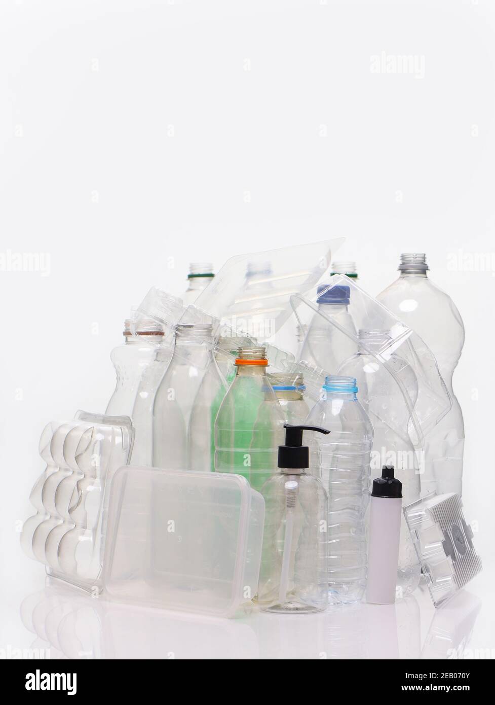 Una collezione di materiale a base di plastica per uso domestico sparato su uno sfondo bianco con riflessi. Flaconi, vassoi per alimenti, contenitori per pompe pronti per il riciclaggio. Foto Stock