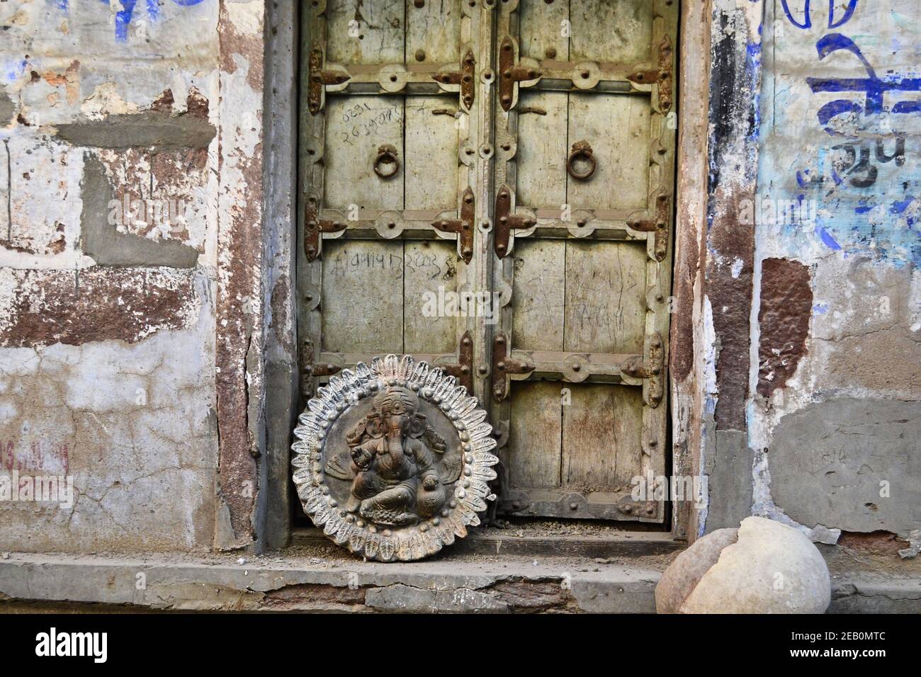 Vecchia porta in legno all'antico edificio vecchio. Simbolo indù arrotondato con immagine del dio Ganesha. Jodhpur, Rajasthan, India. Foto Stock