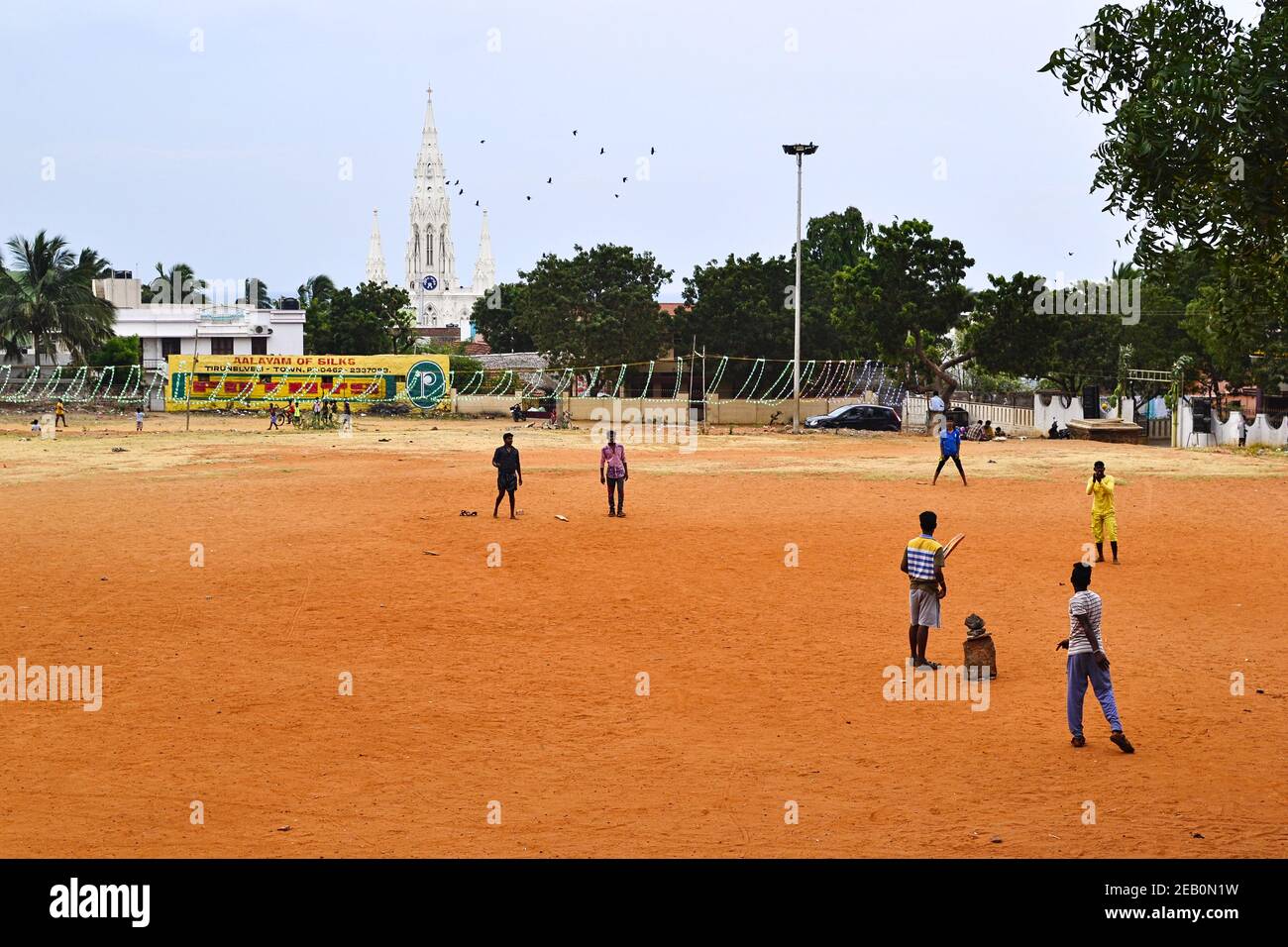 Kanyakumari, Tamil Nadu, India - Gennaio, 2017: Ragazzi indiani che giocano a cricket nel parco giochi. Bianca chiesa cattolica sullo sfondo. Foto Stock