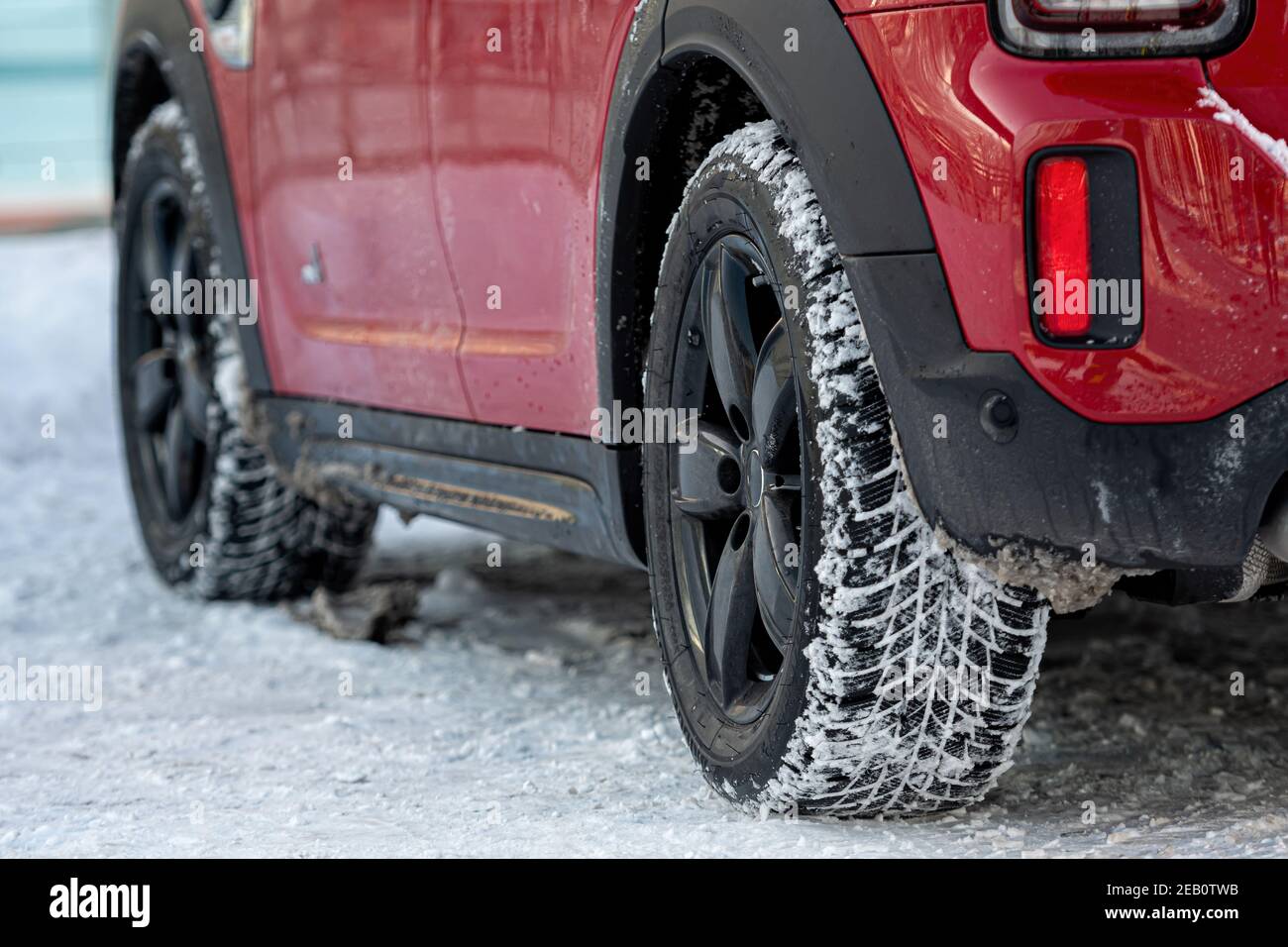 vista ravvicinata posteriore di un'auto rossa in parcheggio, pneumatico della ruota posteriore sporco sulla neve Foto Stock