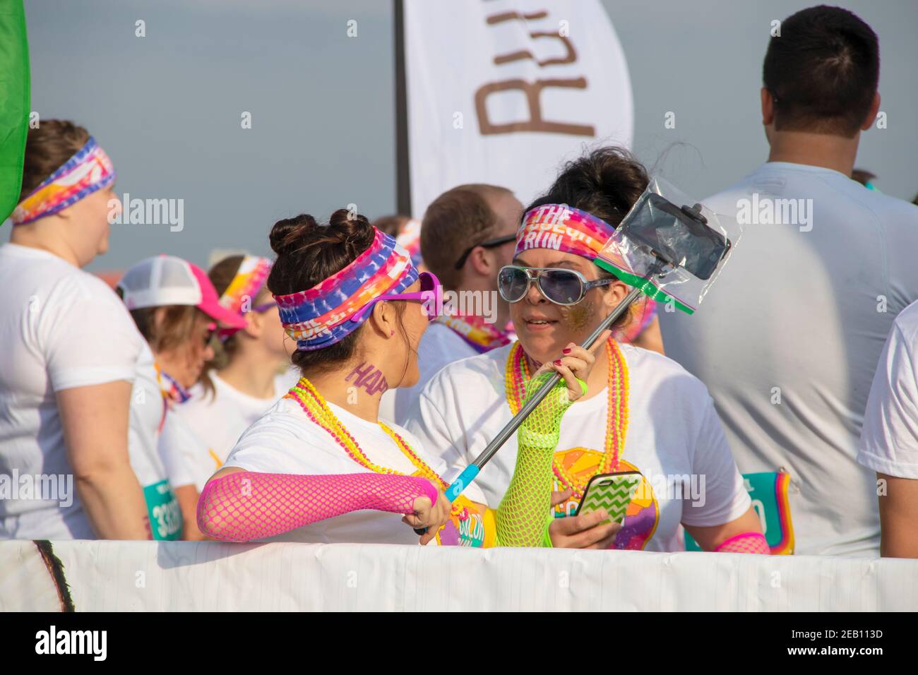 6 aprile 2019 Tulsa USA due donne che ridono e parlano in costume con telefoni e bastone selfie in attesa di inizio Di Serie colore Foto Stock