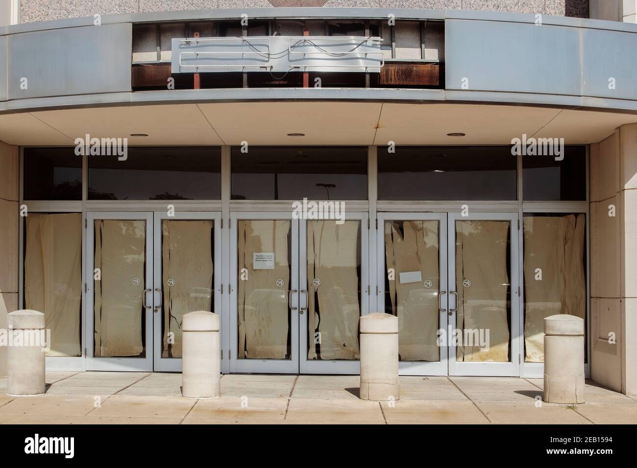 Negozio abbandonato al centro commerciale con carta strappata sopra le porte e. strappato fuori il cartello al neon Foto Stock