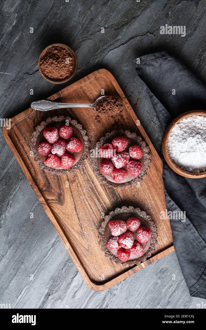 Tartine di crosta di cacao ripieni di mousse al cioccolato fondente fatta di panna montata e purea di lamponi, condite con frutti di bosco freschi, cosparse di polvere Foto Stock