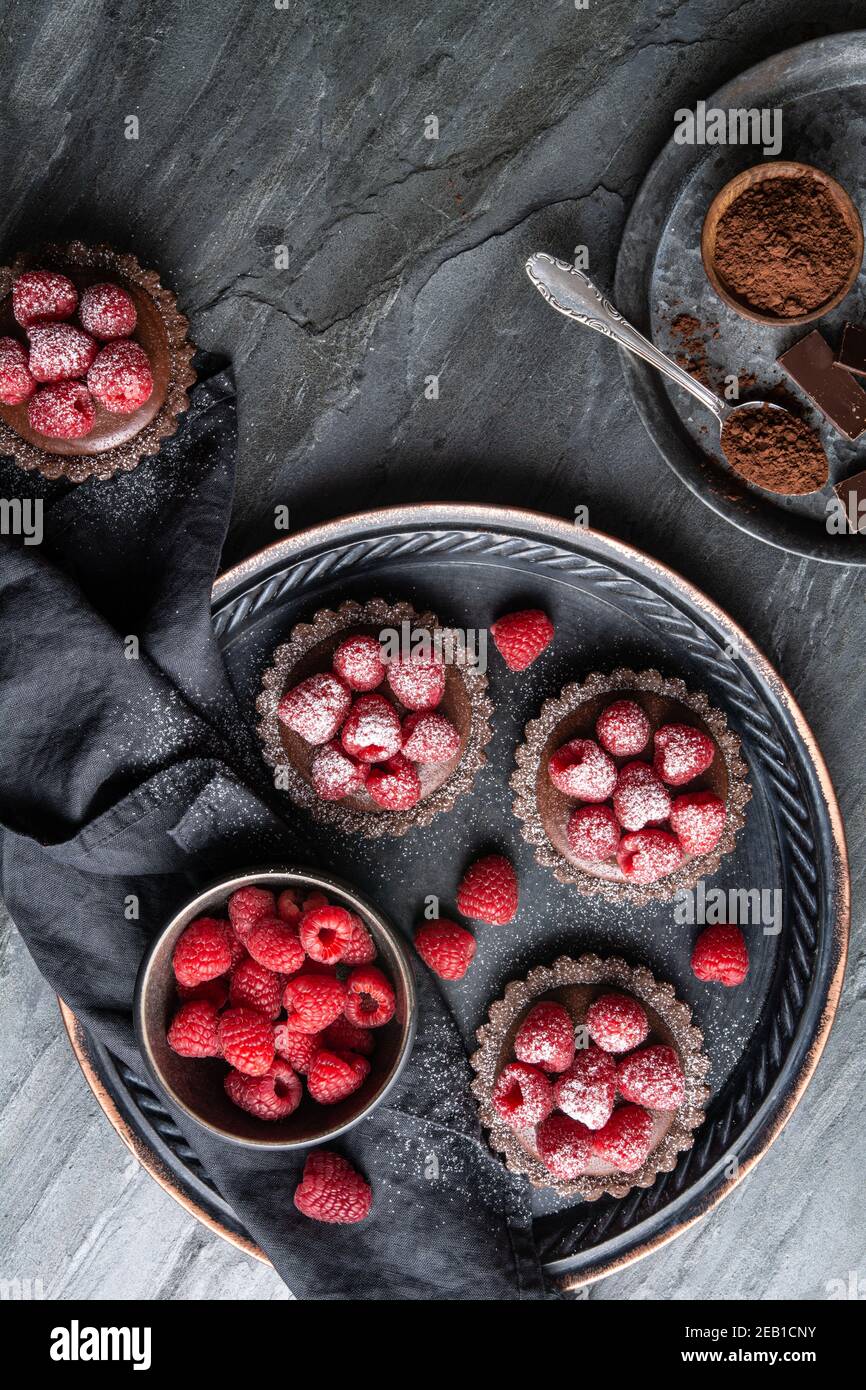 Tartine di crosta di cacao ripieni di mousse al cioccolato fondente fatta di panna montata e purea di lamponi, condite con frutti di bosco freschi, cosparse di polvere Foto Stock