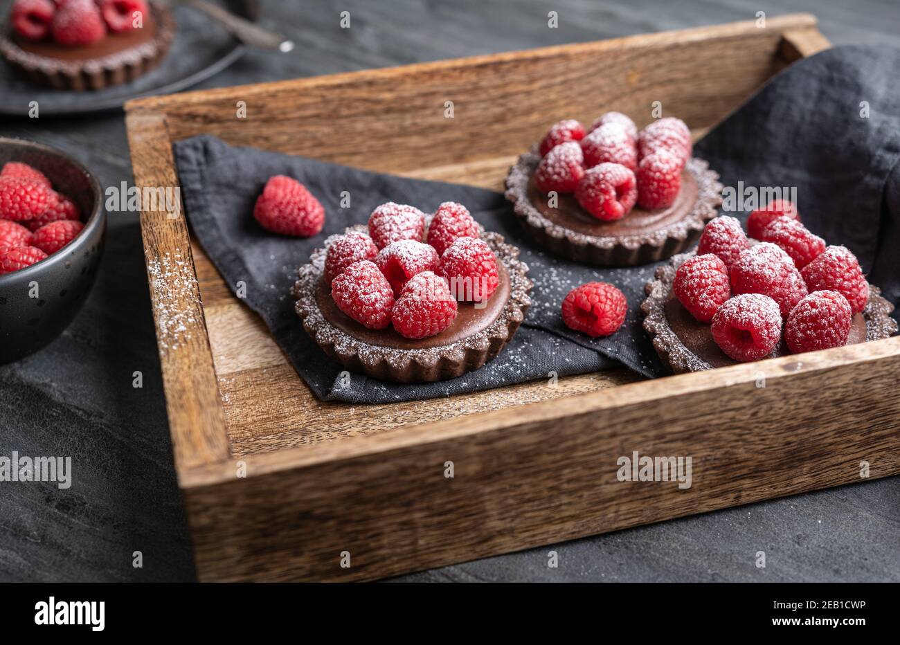Tartine di crosta di cacao ripieni di mousse al cioccolato fondente fatta di panna montata e purea di lamponi, condite con frutti di bosco freschi, cosparse di polvere Foto Stock