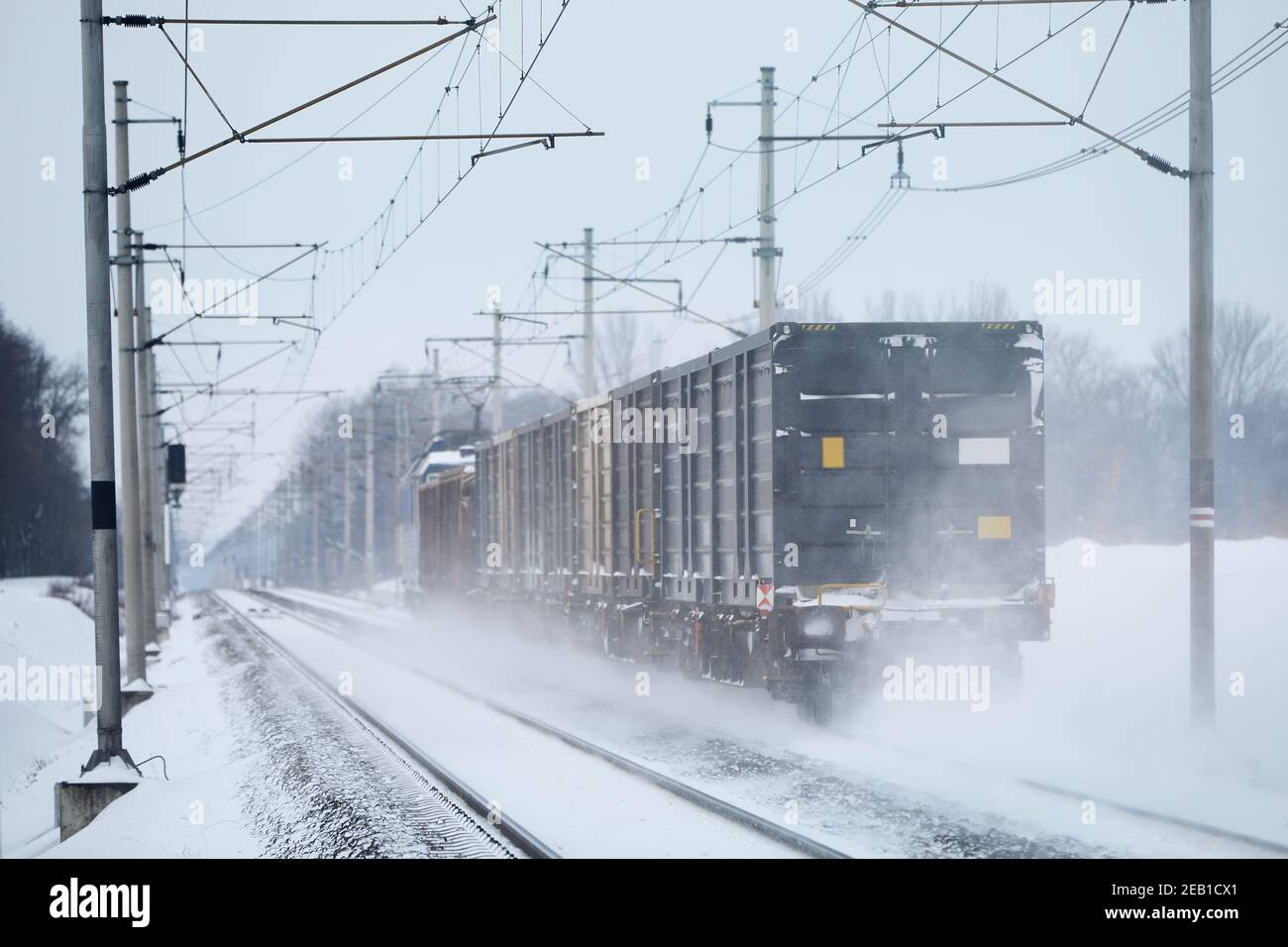 Giornata invernale gelida in treno. Treno merci su pista ferroviaria innevata. Foto Stock