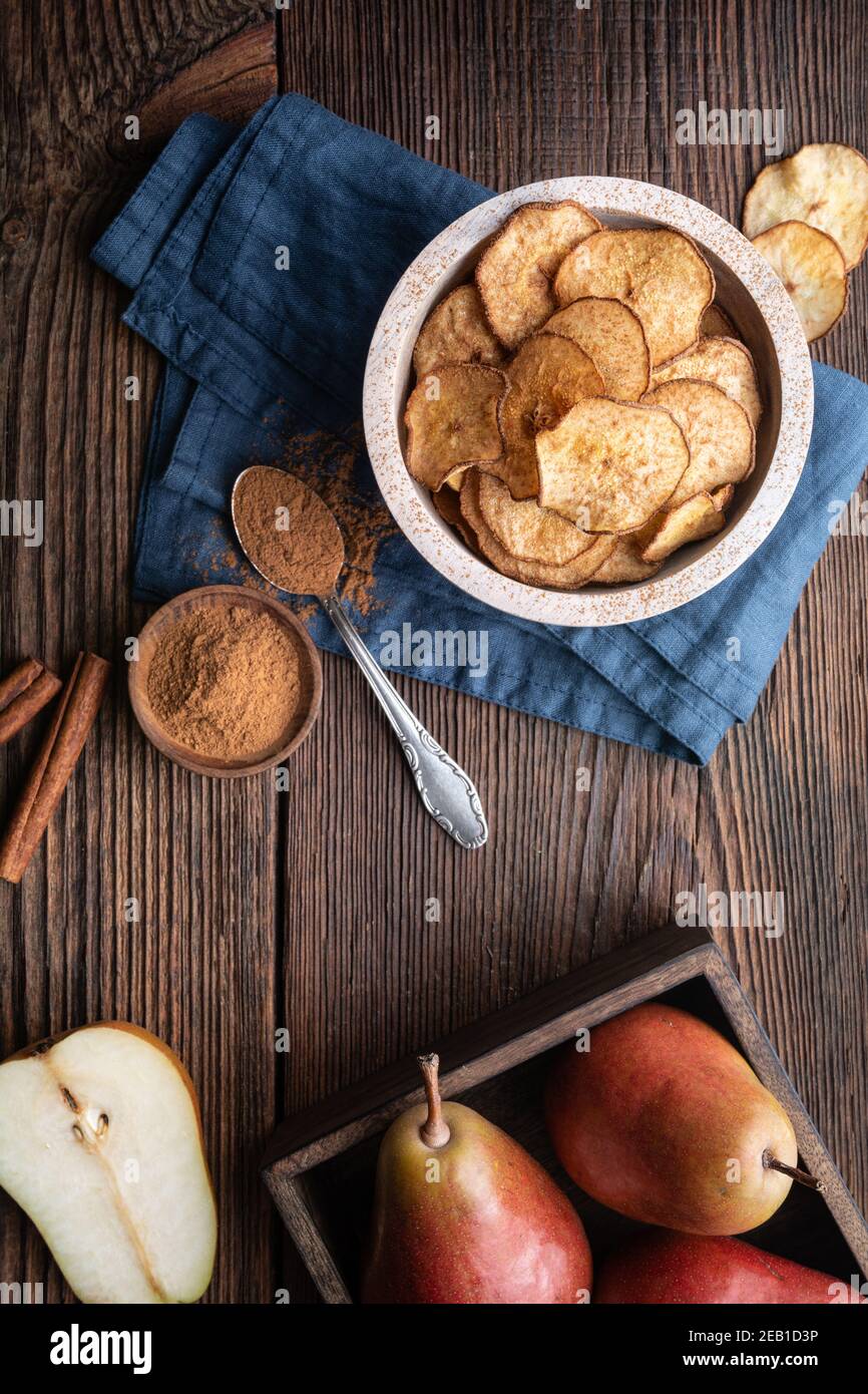 Dolce delizioso spuntino, forno fatto in casa patatine fritte croccanti di pera cosparse di cannella su rustico sfondo di legno Foto Stock