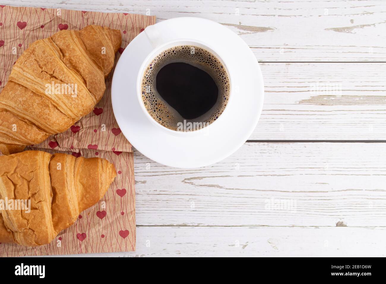 croissant e caffè freschi su sfondo di legno chiaro con spazio per la copia. Foto Stock