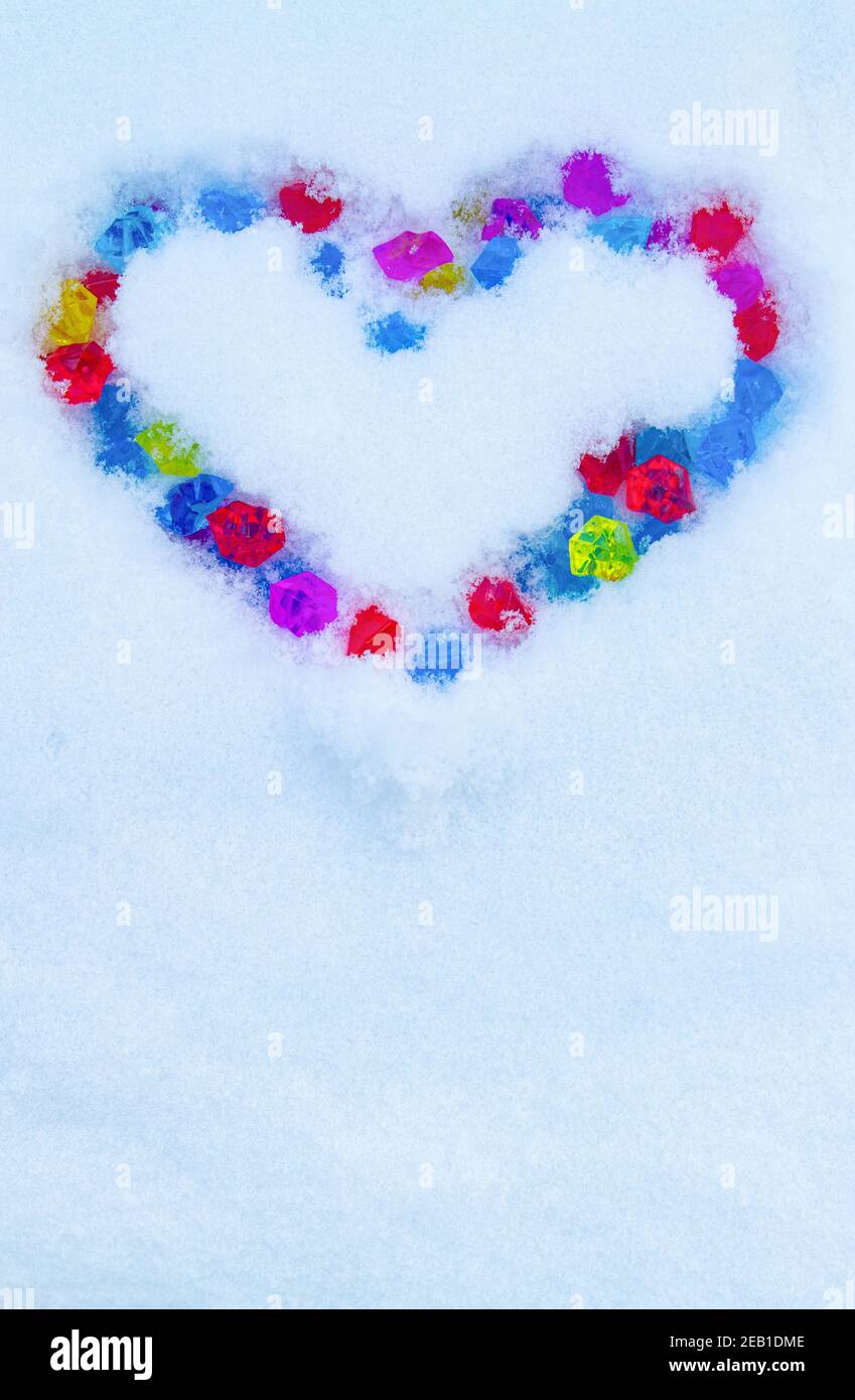 Cuore fatto di cristalli multicolore sulla neve Foto Stock