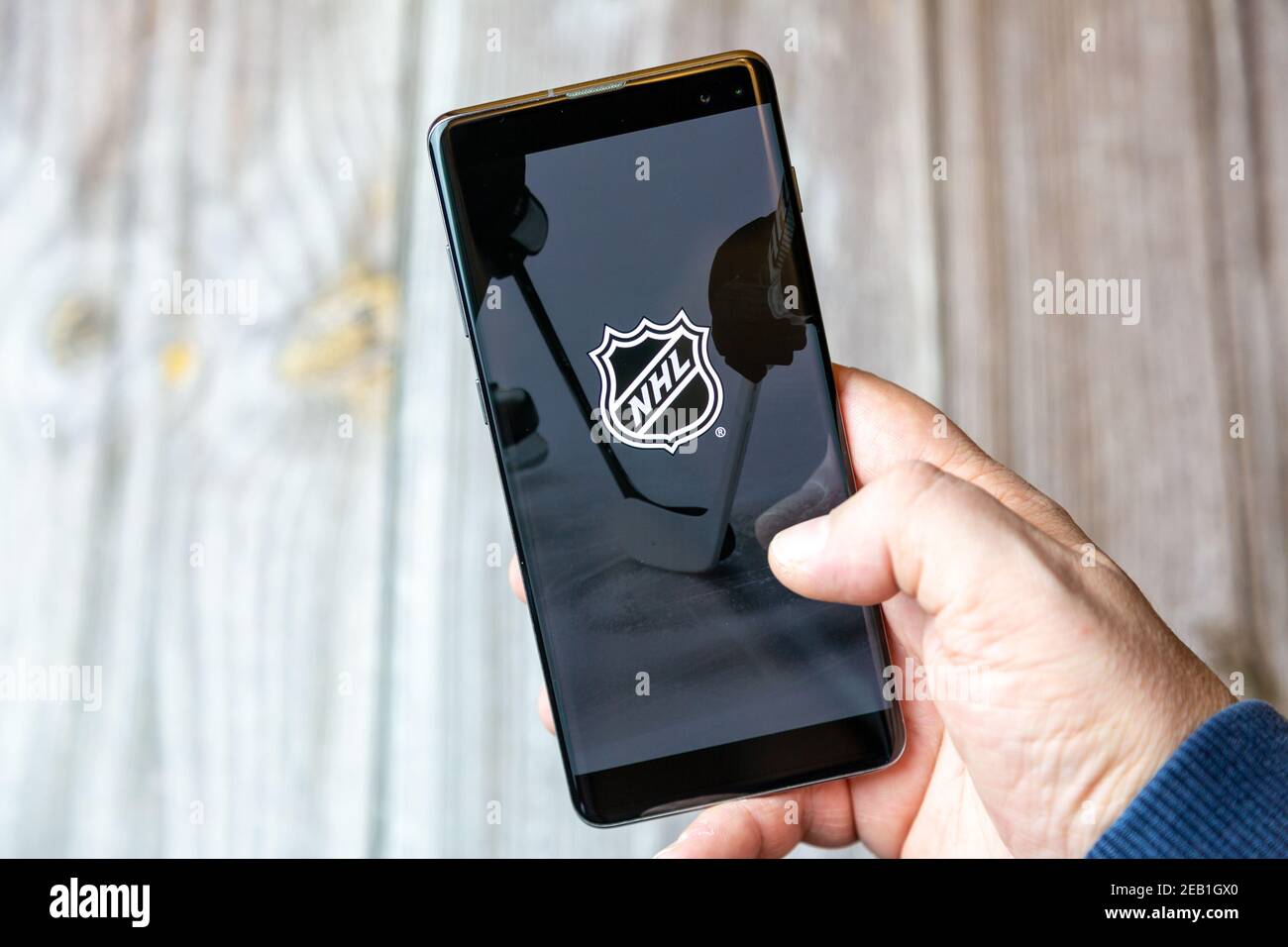 Un telefono cellulare o un telefono cellulare tenuto da un Mano con l'app NHL Hockey aperta sullo schermo Foto Stock